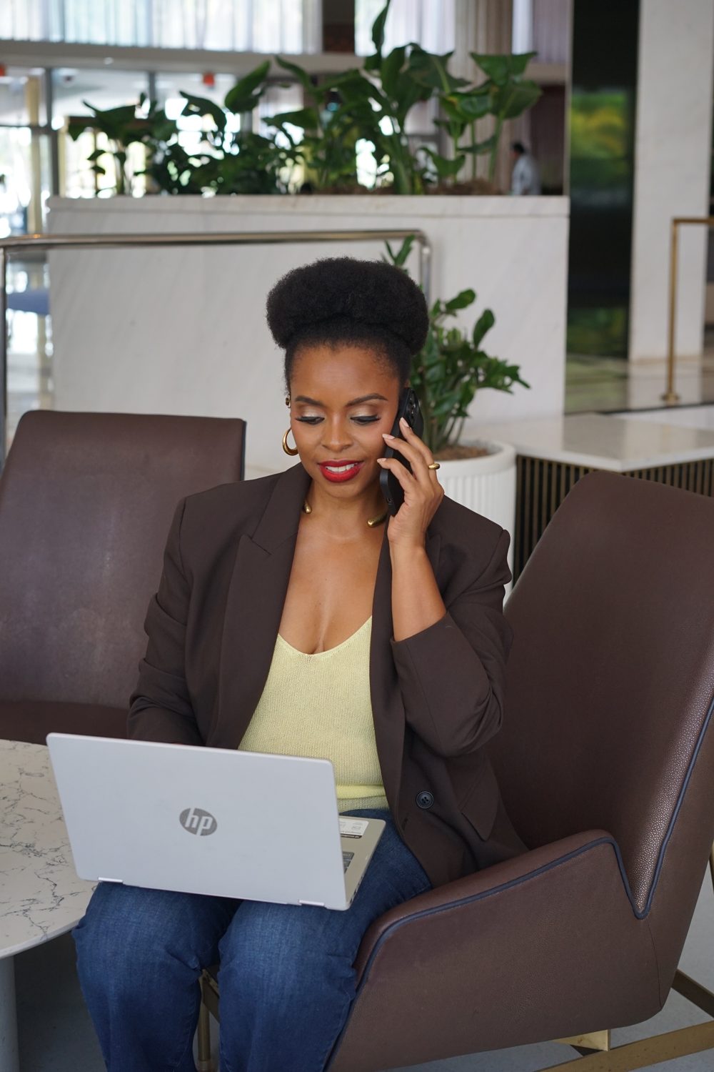 Personal brand client working on a laptop and taking a call in a hotel lobby
