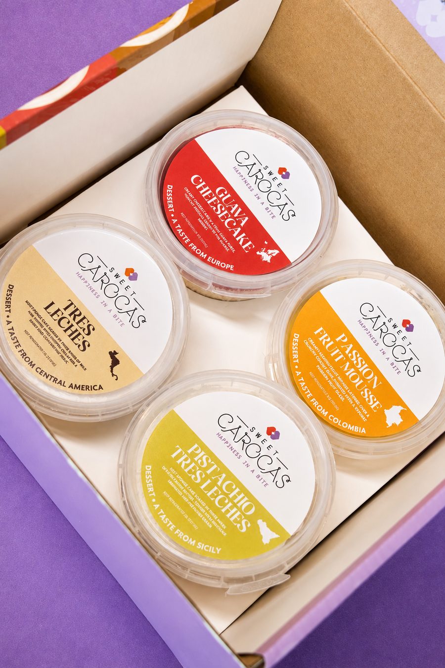 Open gift box holding four labeled dessert cups on a purple background