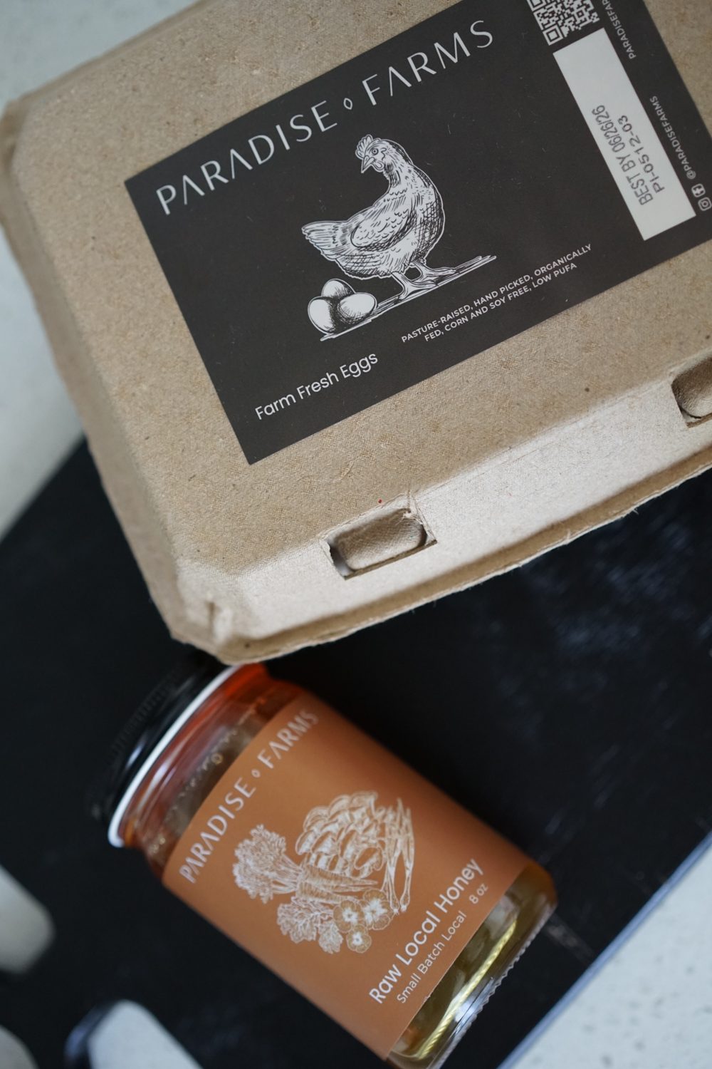 Paradise Farms farm fresh eggs and raw local honey on a black cutting board