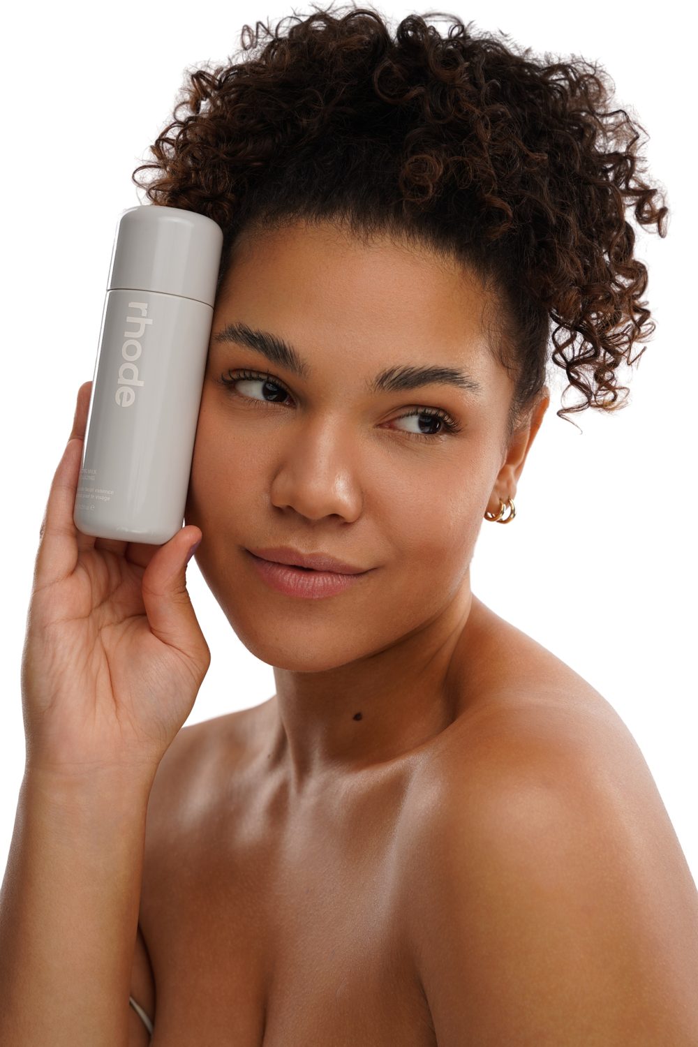 Model holding a skincare bottle against her cheek in a clean beauty shot