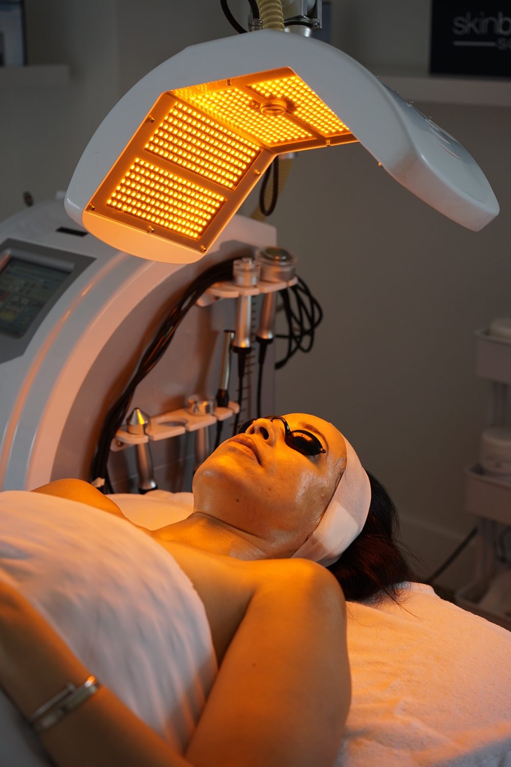 Client relaxing under an LED light during an esthetician facial